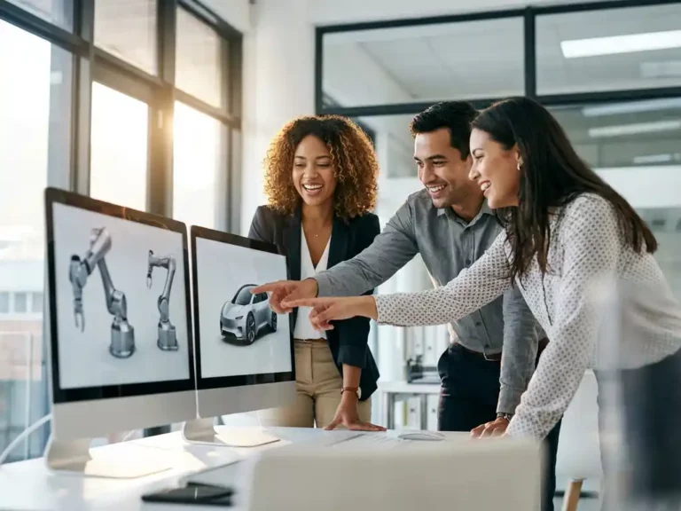 Drei lächelnde Fachkräfte betrachten Industriedesign-Konzepte auf Computermonitoren in modernem, lichtdurchflutetem Büro.